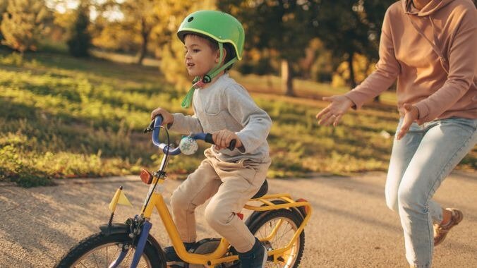 (Imaage d'une maman qui lance son enfant à vélo sans le tenir)